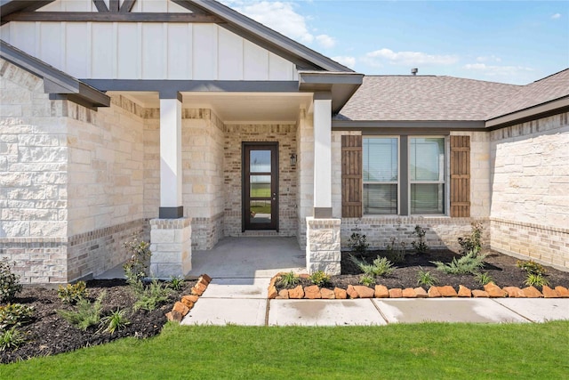 property entrance featuring roof with shingles, a porch, board and batten siding, and brick siding