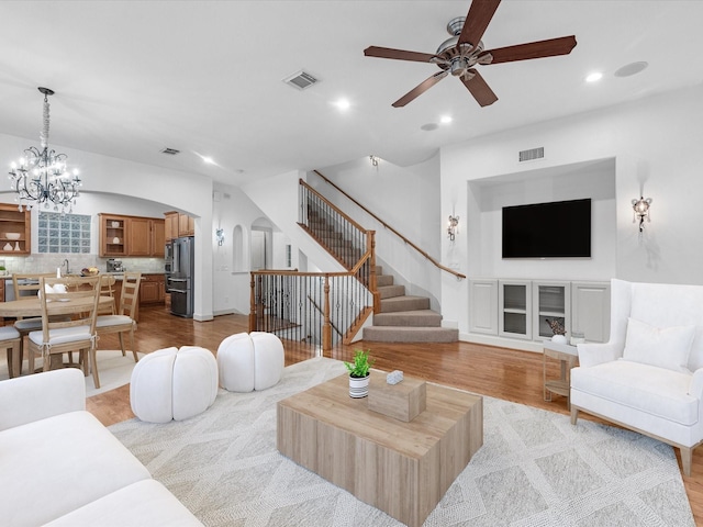 living room with sink, ceiling fan with notable chandelier, and light hardwood / wood-style floors