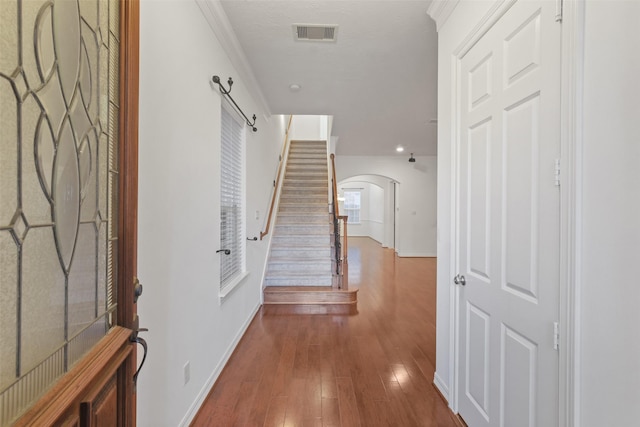 foyer entrance with wood-type flooring and crown molding