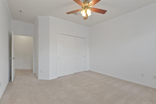 unfurnished bedroom with ceiling fan, a closet, light carpet, and ornamental molding