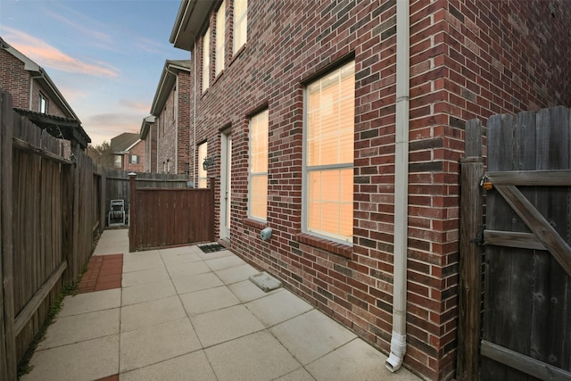 property exterior at dusk featuring a patio area