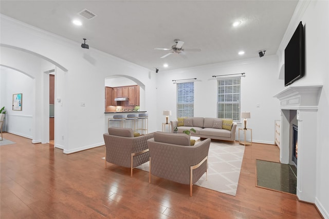 living room with ceiling fan, crown molding, and light hardwood / wood-style flooring