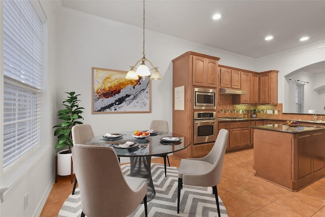 kitchen featuring dark stone counters, hanging light fixtures, decorative backsplash, light tile patterned floors, and stainless steel appliances