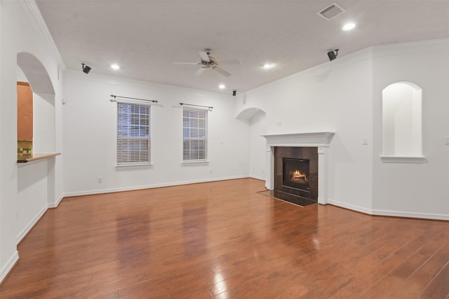 unfurnished living room featuring ceiling fan, a fireplace, wood-type flooring, and ornamental molding