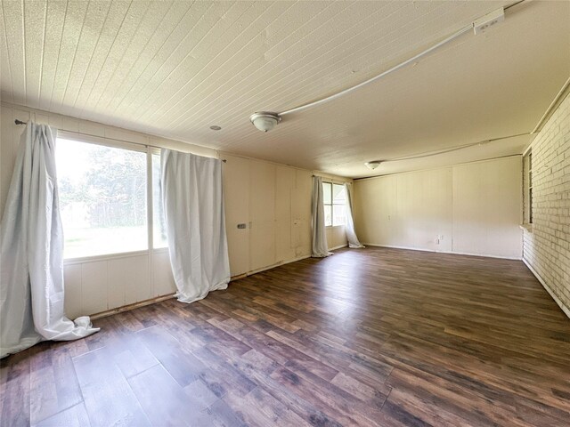 empty room with wooden ceiling, brick wall, and dark hardwood / wood-style floors