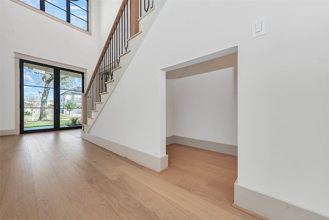 interior space with stairway, wood finished floors, baseboards, and a towering ceiling