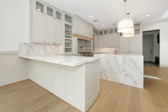 kitchen featuring light stone countertops, a peninsula, recessed lighting, decorative backsplash, and light wood-style floors