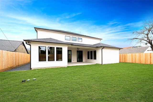 rear view of property with a lawn, a patio, a shingled roof, and a fenced backyard