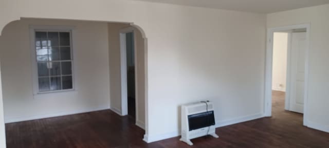 empty room with heating unit and dark hardwood / wood-style flooring