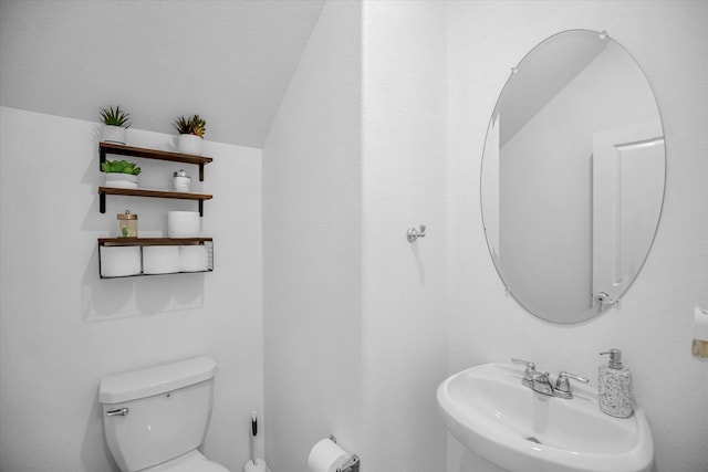 bathroom with toilet, vaulted ceiling, and sink