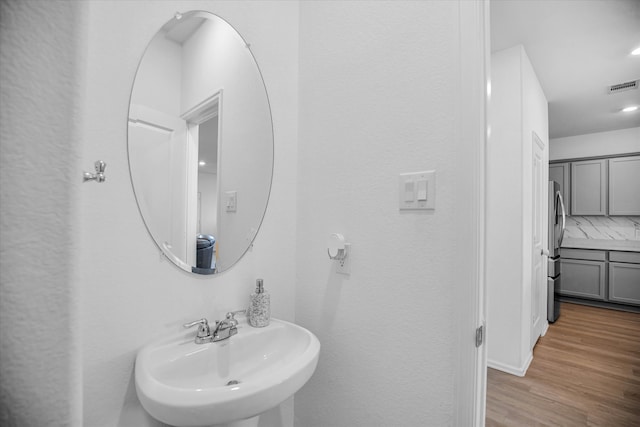 bathroom featuring hardwood / wood-style flooring, sink, and tasteful backsplash