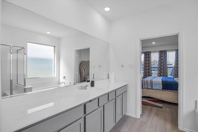 bathroom featuring plus walk in shower, hardwood / wood-style floors, and vanity