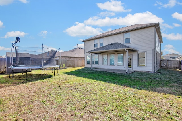 rear view of house featuring a yard, a trampoline, and a patio