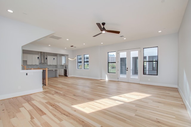 unfurnished living room with french doors, light hardwood / wood-style flooring, and ceiling fan