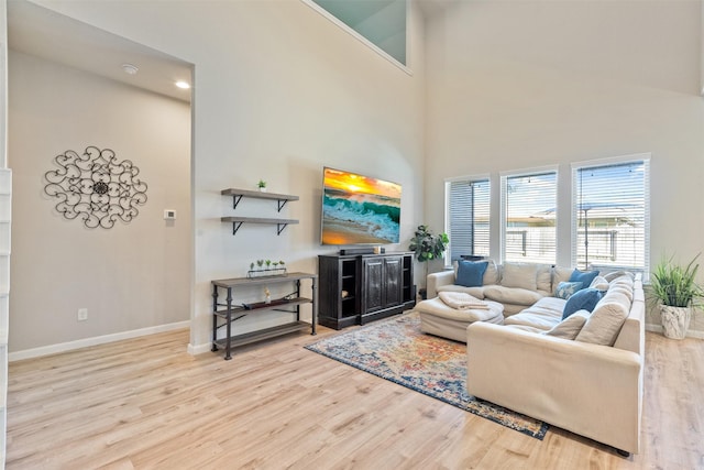 living room featuring a towering ceiling and light wood-type flooring