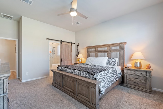 carpeted bedroom with ceiling fan, a barn door, and connected bathroom