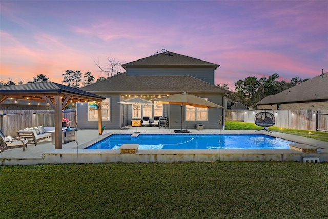 pool at dusk featuring a yard, a patio, and a gazebo