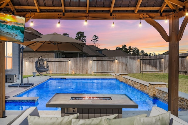 pool at dusk featuring a fire pit