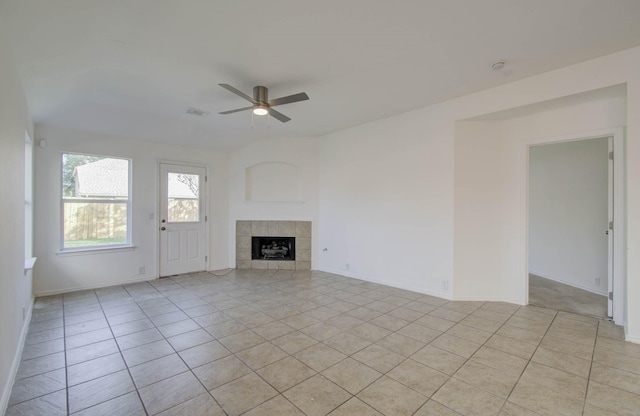 unfurnished living room with a tiled fireplace, ceiling fan, and light tile patterned floors