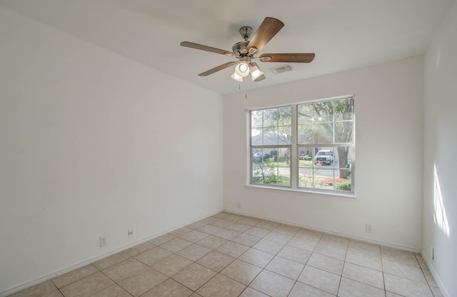 tiled spare room featuring ceiling fan