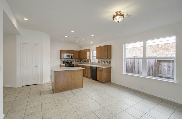 kitchen with a kitchen island, tasteful backsplash, vaulted ceiling, light tile patterned flooring, and black appliances