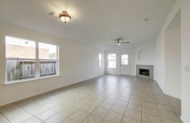 unfurnished living room featuring a tile fireplace, ceiling fan, and light tile patterned flooring