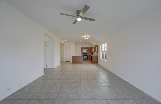 unfurnished living room with ceiling fan, light tile patterned floors, and vaulted ceiling