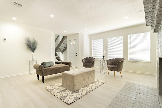 living room featuring light wood-type flooring and a textured ceiling