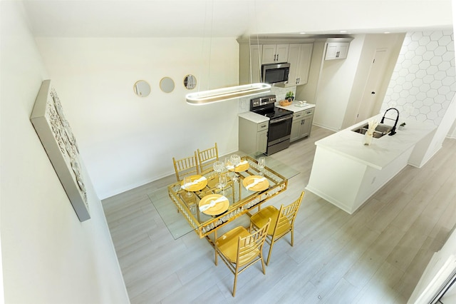 kitchen with light wood-type flooring, stainless steel appliances, gray cabinets, and sink