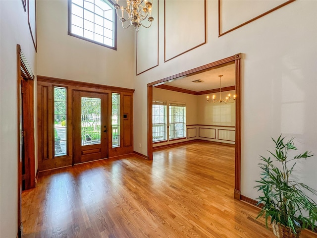 entryway with a wealth of natural light, hardwood / wood-style flooring, a high ceiling, and an inviting chandelier