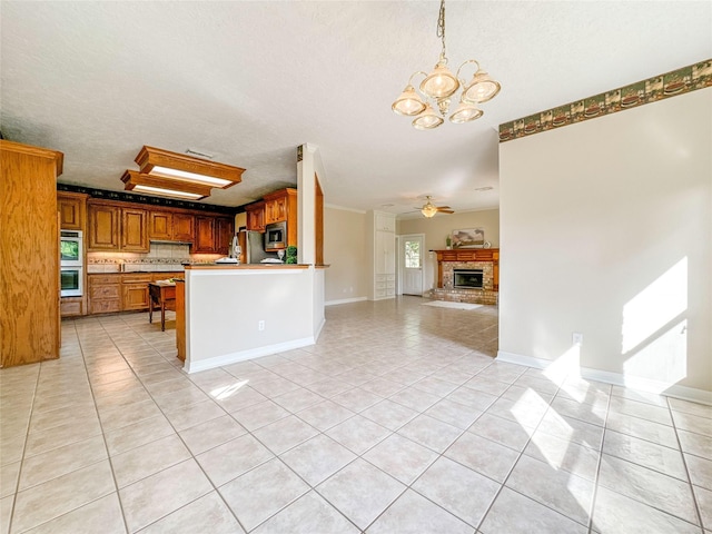 kitchen featuring kitchen peninsula, appliances with stainless steel finishes, ceiling fan with notable chandelier, light tile patterned floors, and pendant lighting