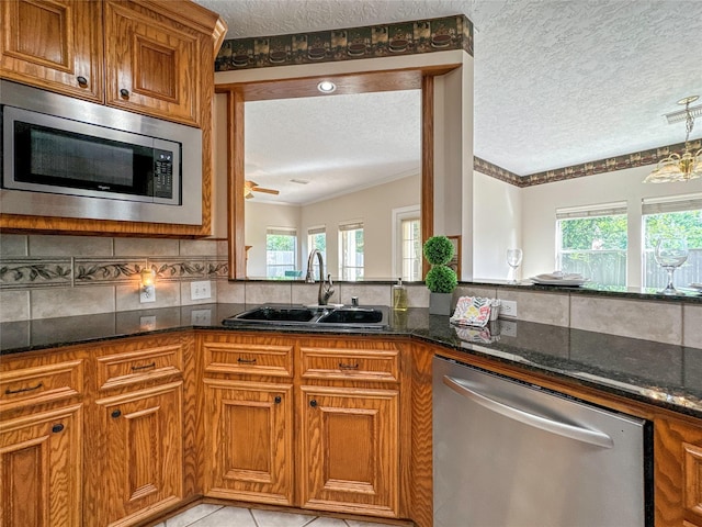 kitchen featuring a textured ceiling, dark stone countertops, sink, and stainless steel appliances