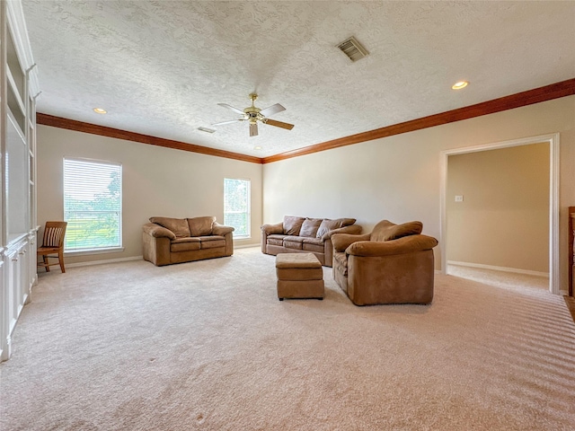 carpeted living room with ceiling fan, plenty of natural light, a textured ceiling, and ornamental molding