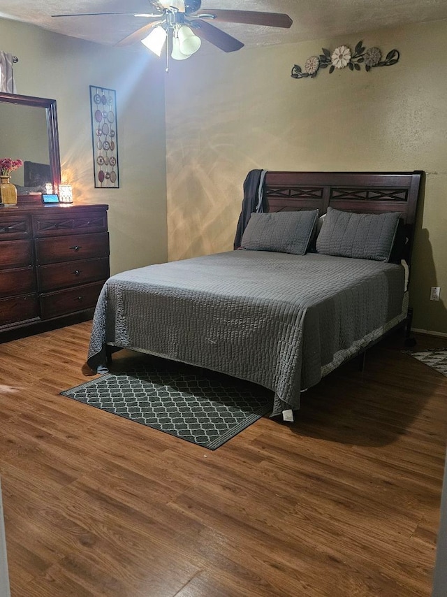 bedroom featuring ceiling fan, hardwood / wood-style floors, and a textured ceiling