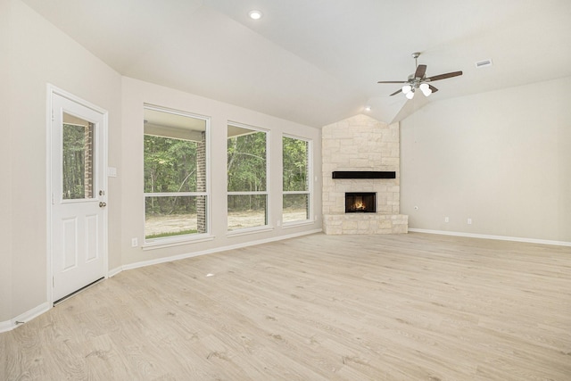 unfurnished living room featuring light hardwood / wood-style flooring, ceiling fan, lofted ceiling, and a stone fireplace