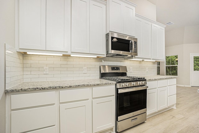 kitchen with decorative backsplash, white cabinetry, appliances with stainless steel finishes, and light hardwood / wood-style flooring