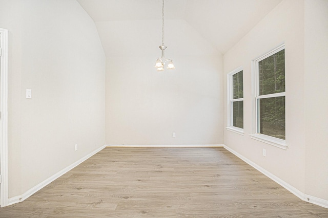 spare room featuring light hardwood / wood-style floors, vaulted ceiling, plenty of natural light, and a notable chandelier