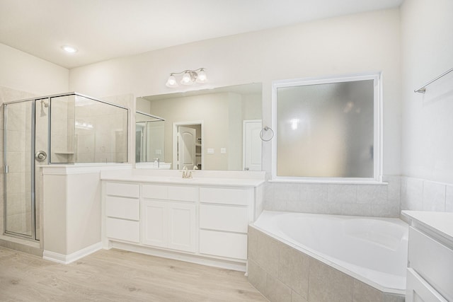 bathroom with hardwood / wood-style flooring, vanity, and shower with separate bathtub