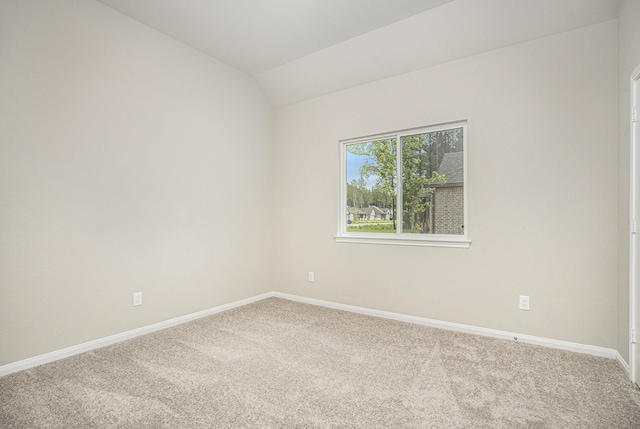 carpeted empty room with vaulted ceiling