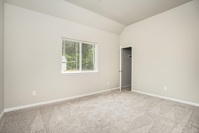 unfurnished room featuring light colored carpet and vaulted ceiling