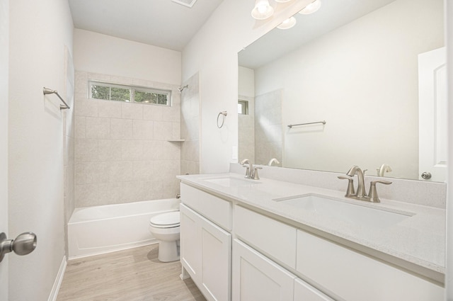 full bathroom with hardwood / wood-style floors, tiled shower / bath combo, toilet, and vanity