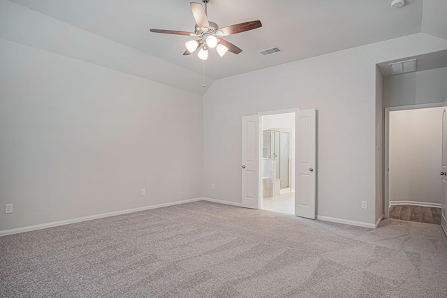 unfurnished bedroom featuring vaulted ceiling, light colored carpet, ensuite bath, and ceiling fan