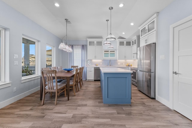 kitchen with a center island, white cabinets, sink, hanging light fixtures, and stainless steel appliances