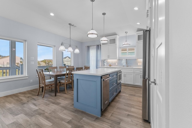 kitchen featuring a center island, blue cabinets, hanging light fixtures, tasteful backsplash, and white cabinetry