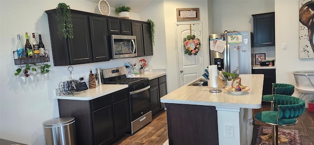 kitchen featuring a breakfast bar area, a kitchen island with sink, appliances with stainless steel finishes, and dark wood-type flooring