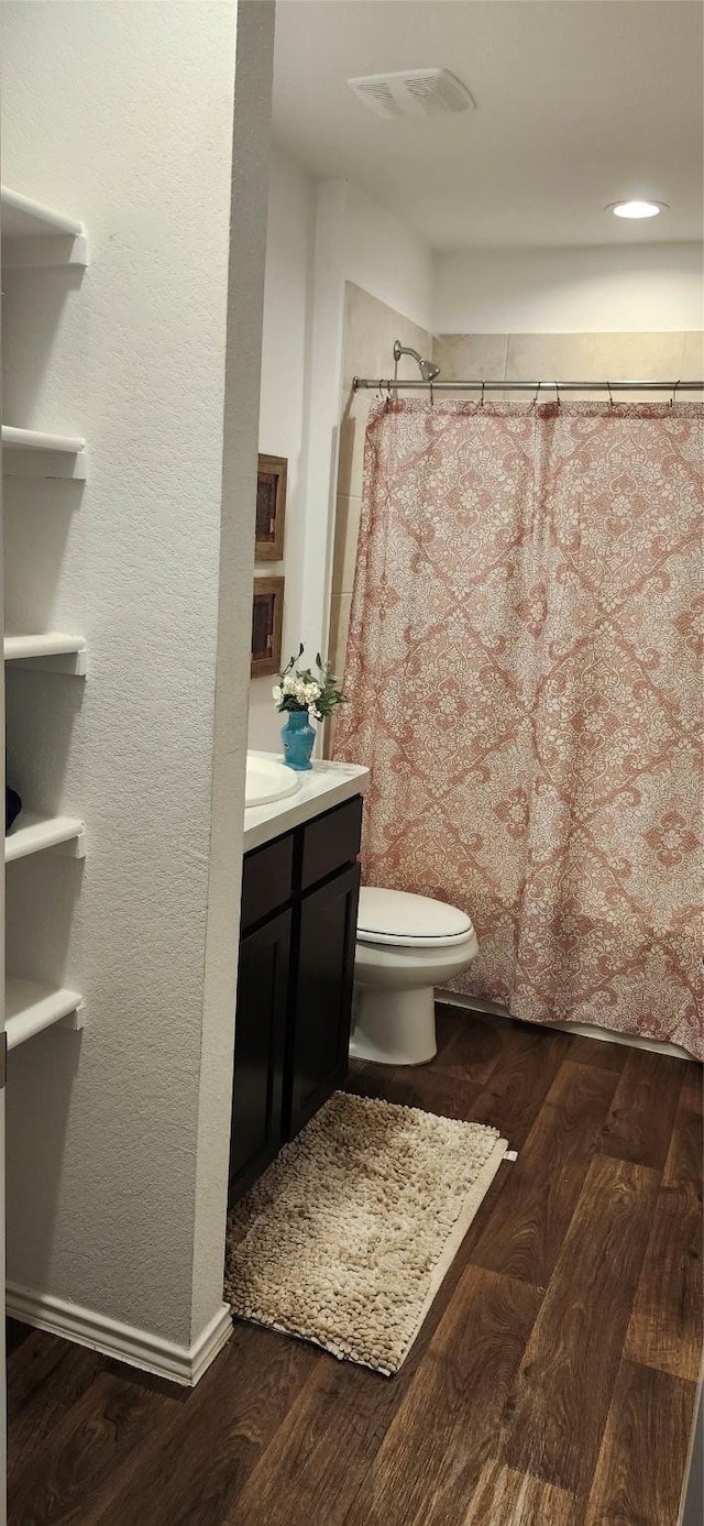 bathroom featuring vanity, hardwood / wood-style flooring, toilet, and walk in shower