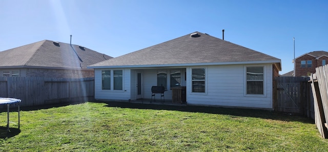 back of property featuring a trampoline, a patio area, and a lawn