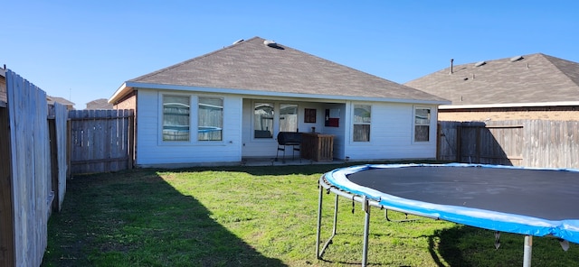 rear view of property featuring a lawn and a trampoline