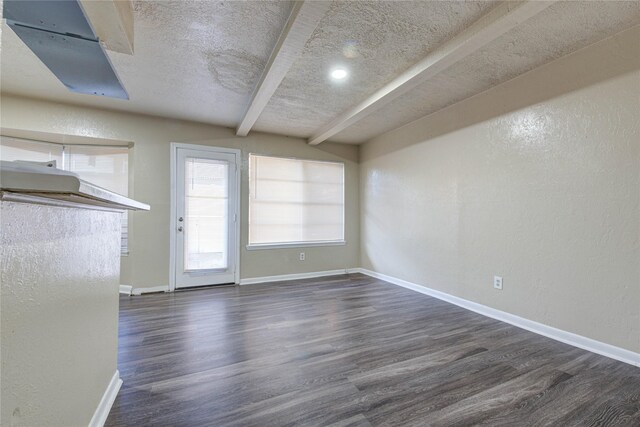 unfurnished dining area with beamed ceiling, dark hardwood / wood-style floors, and a textured ceiling