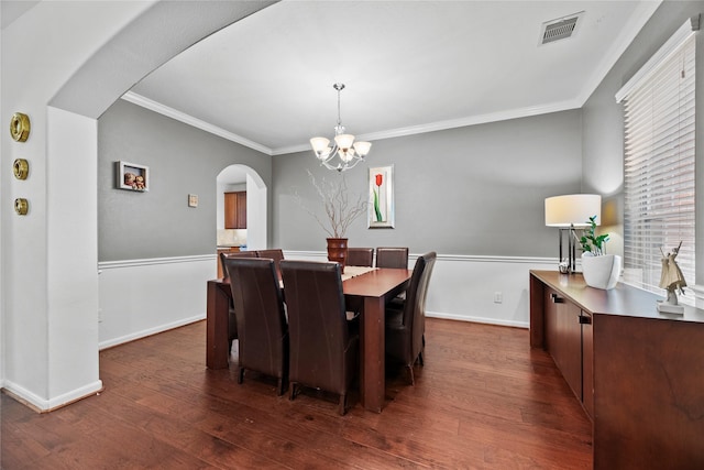 dining area with an inviting chandelier, dark wood-type flooring, and ornamental molding